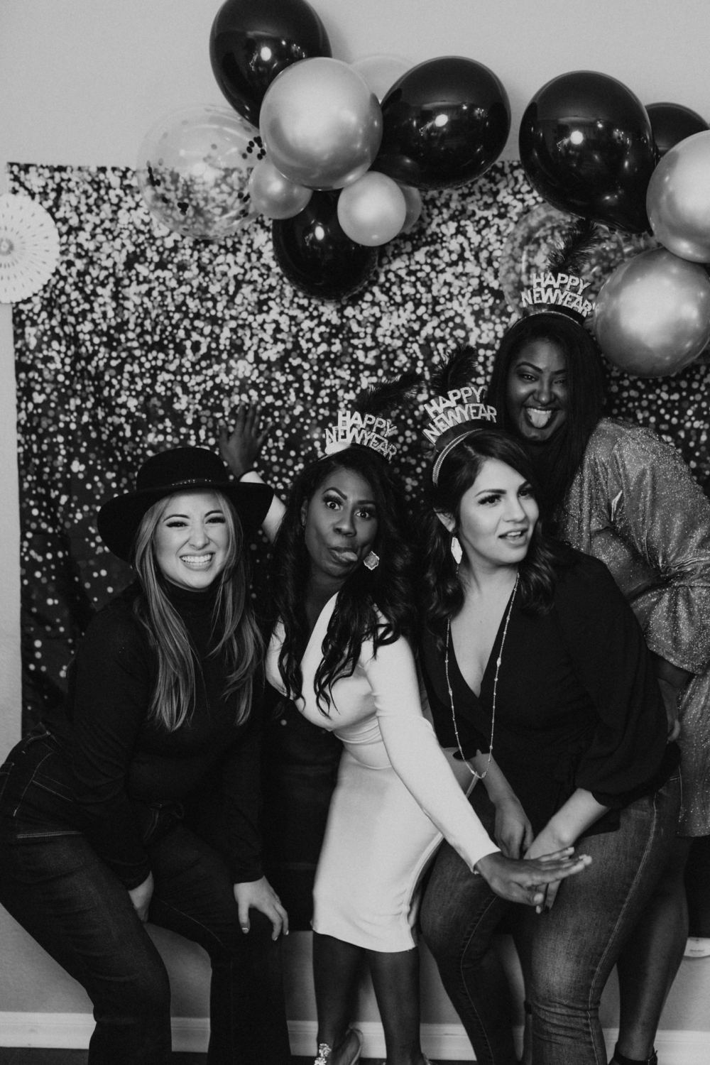 Friends posing at a balloon photo booth backdrop