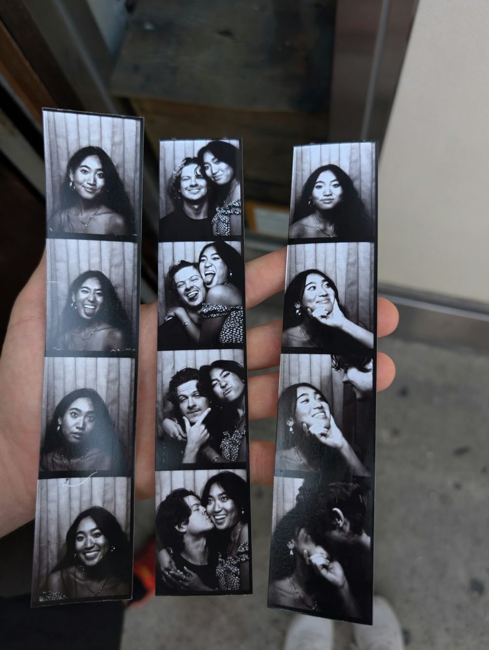 Hand holding black and white photo booth strips
