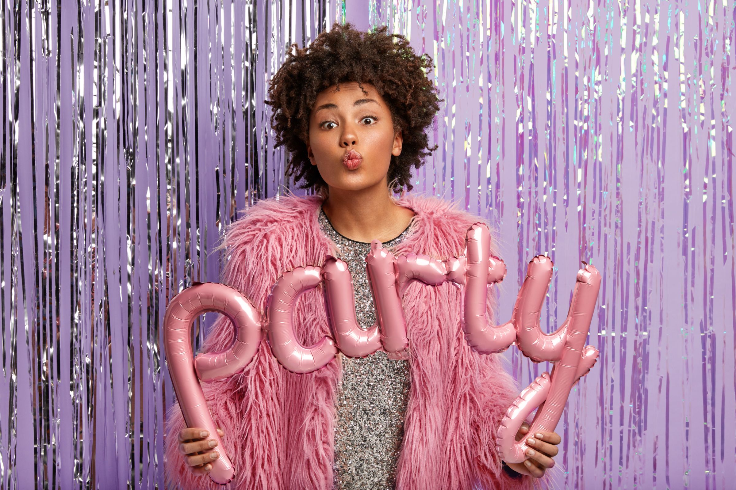 Guest posing with party balloons in front of a shimmering photo booth backdrop